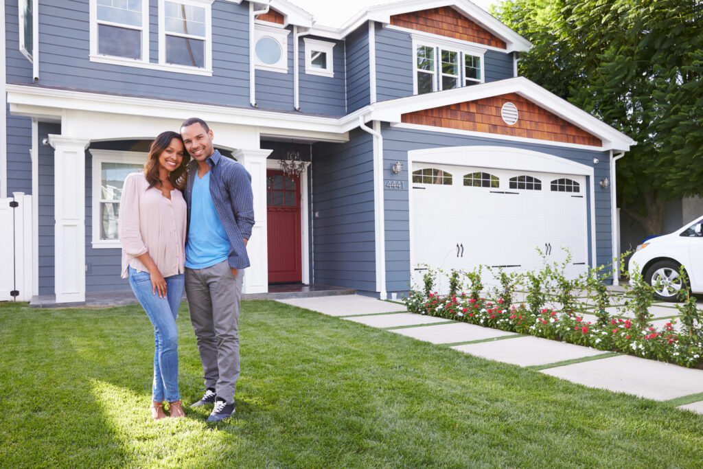 happy black couple standing in front of their new home, what to do when mortgage rates increase